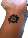 pentagram and sun tattoo on wrist